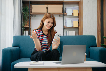 Fototapeta na wymiar Young attractive Asian woman smiling thinking planning writing in notebook, tablet and laptop working from home at office .