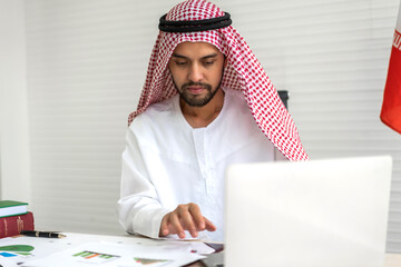 Handsome confident arab businessman working and looking at laptop computer.Creative coworkers...