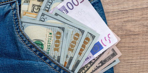 dollar and euro bills inside jeans pocket.