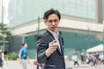 An irate young chinese man confronts and points at someone. Making heated demands and putting down...