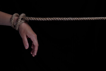 Tied hands with a rope on a black background. copy space for text