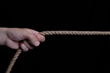 hand pulling a rope on black background