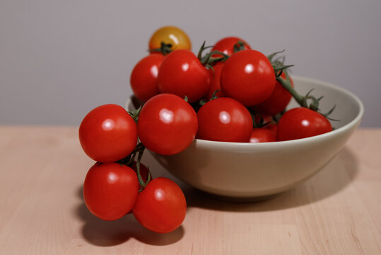 Fresh red tomatoes in a plate on a wooden table