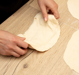 Female hands kneading dough on a wooden table. Close-up
