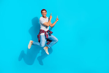Fototapeta na wymiar Full body portrait of cheerful crazy man jumping indicate fingers empty space proposition isolated on blue color background