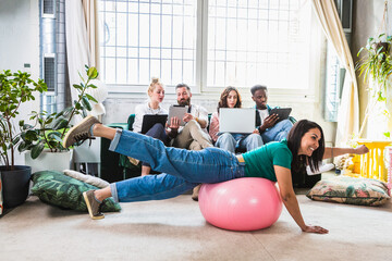 Bizarre scene with boys studying on the computer and a girl playing with a pilates ball