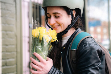 Happy delivery person smelling bouquet of flowers
