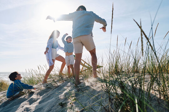Parents playing with children at beach on sunny day - Powered by Adobe
