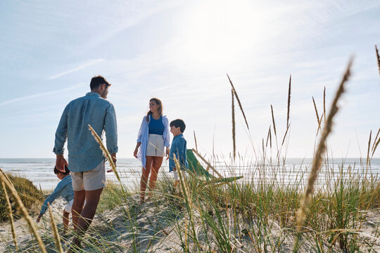 Parents and children spending leisure time at beach on sunny day