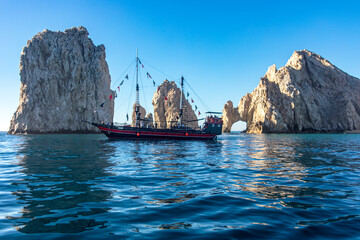 Fototapeta premium Sailboat in the arch of Cape Saint Luke, a famous rock formation known for being where the Cortez Sea meets the Pacific Ocean, in the state of Baja California Sur, Mexico. Arch concept.
