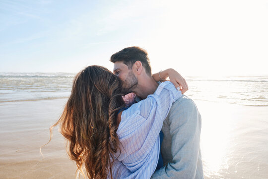 Romantic couple embracing and kissing at beach