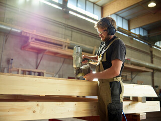 Carpenter using nail tool on timber in workshop