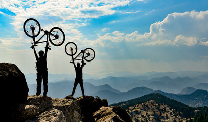 two friends biking to the summits of the mountains and celebrating the victory - 616915843