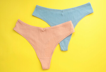 Сoncept of women's natural underwear. Women's panties made of pastel cotton on yellow background. Top view, level position