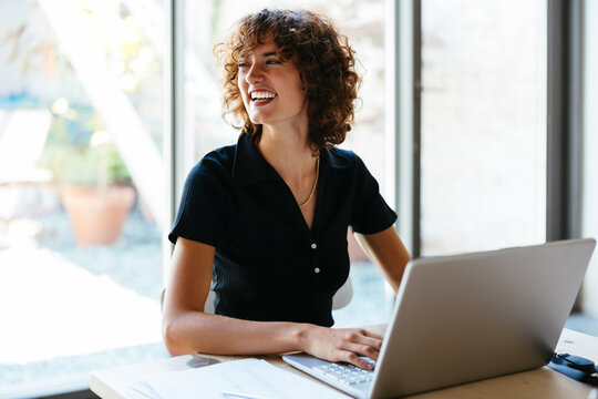 Happy Young Businesswoman Sitting With Laptop At Desk