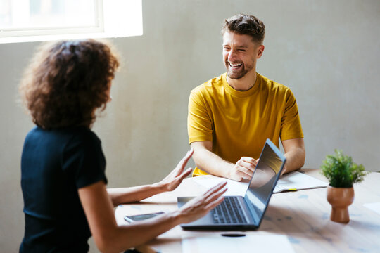 Happy businessman having discussion with businesswoman at desk