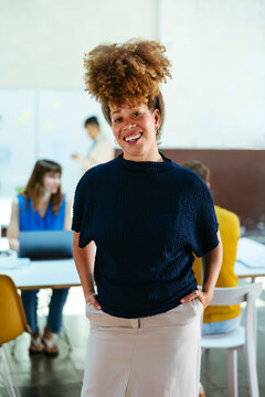 Happy businesswoman standing with hands in pockets