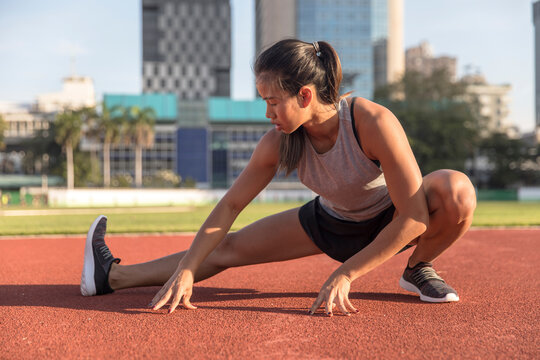 Young woman doing leg exercise in sports field - Powered by Adobe