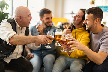 Happy friends toasting beer together at home