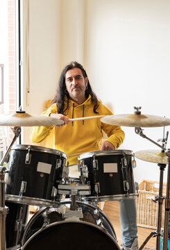 Smiling mature musician playing drum at home