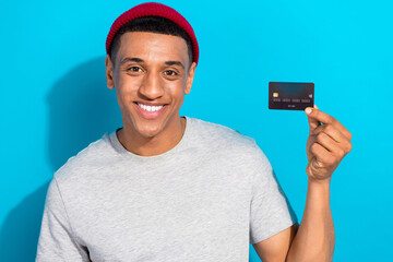 Photo of friendly positive person toothy smile hand hold demonstrate plastic debit card isolated on blue color background