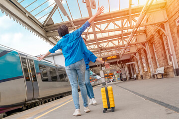 Fototapeta premium Beautiful couple at railway station waiting for the train. Woman and man running to board a train