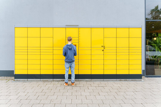 Boy standing in front of parcel locker