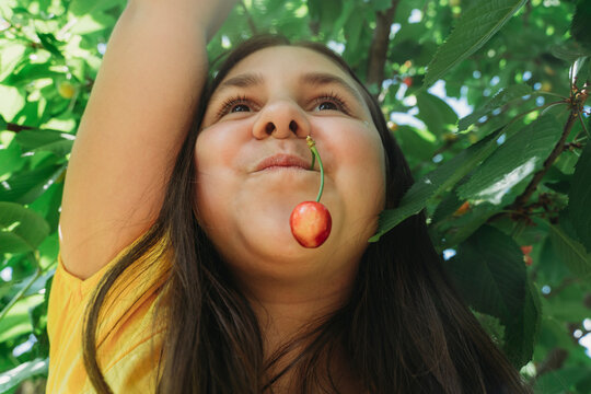 Happy girl with cherry in mouth