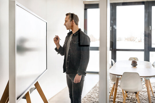 Businessman with digitized pen working on interactive whiteboard