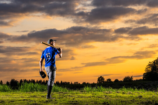 Sporty man holding baseball bat at dusk
