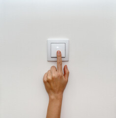 Female finger on light switch close-up.