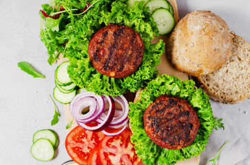 Freshly Grilled Burger Patties,Plant Based Meatless Burgers with Fresh Vegetables on a Wooden Board on Bright Background