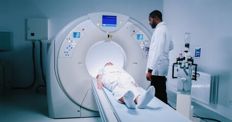 Woman lies on MRI capsule table. Examination of magnetic resonance imaging at background of...