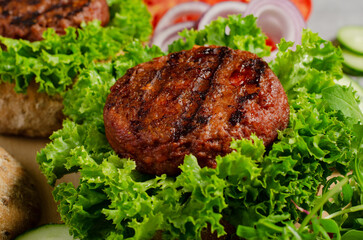 Freshly Grilled Burger Patties,Plant Based Meatless Burgers with Fresh Vegetables on a Wooden Board on Bright Background