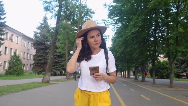 A traveler girl is looking for a way in an unfamiliar city using a phone and maps. Tourism, visiting new places, communication with passers-by. Modern technologies, digitalization, mobile phone naviga