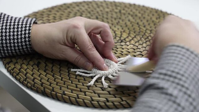 the craftswoman weaves macrame with her hands in the style of a Christmas tree toy