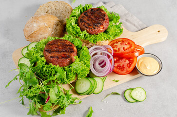 Freshly Grilled Burger Patties,Plant Based Meatless Burgers with Fresh Vegetables on a Wooden Board on Bright Background