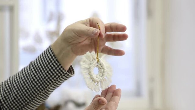 the craftswoman weaves macrame with her hands in the style of a Christmas tree toy