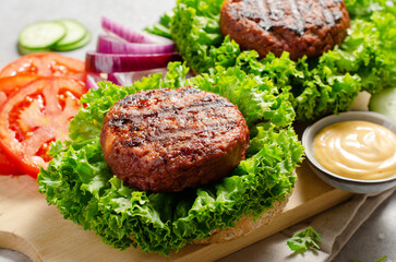 Freshly Grilled Burger Patties,Plant Based Meatless Burgers with Fresh Vegetables on a Wooden Board on Bright Background