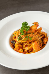 Shrimp spaghetti on white porcelain plate on black stone table