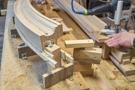 Bending wooden staircase handrail made of oak planks and plywood on table closeup. Detail of stairs fence in carpentry workshop