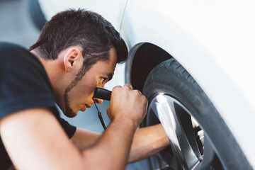 Car mechanic working in workshop checking engine