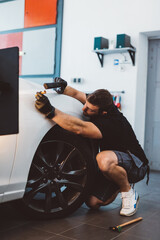 Car mechanic working to remove dent in workshop.