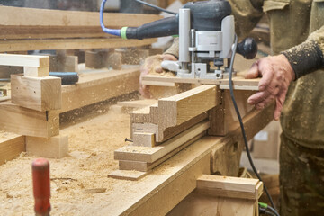 Carpenter milling wooden handrail with router manual milling machine in workshop close up. Handyman...