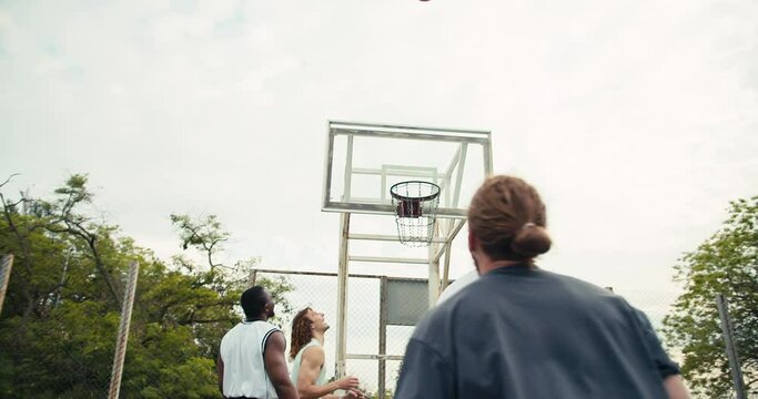 Redhead Man dribbles in a basketball game, he tries to hit the basket, but he fails. His team support him and they try again