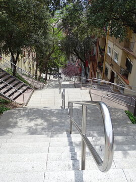 Calle con mucha pendiente con bloques de pisos a los lados, tiene barandillas de acero inoxidable, escalones y &aacute;rboles  