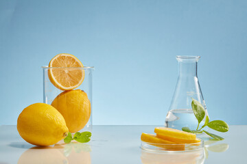 Laboratory glassware decorated with lemon and lemon slices on the mirror table. Blank space in the middle for product presentation of Lemon (Citrus limon) extract