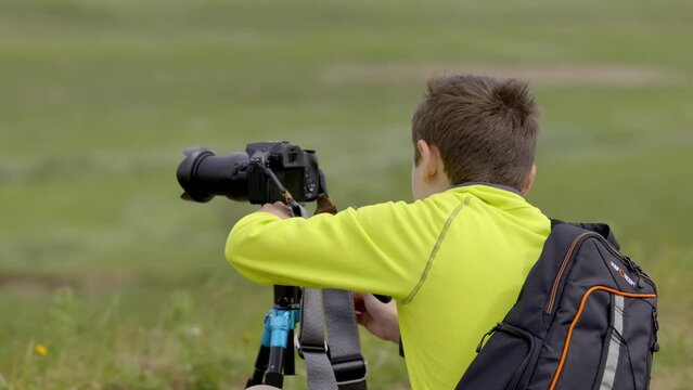 Young boy, photographer setting up his tripod for wildlife video production