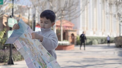 Happy asian boy put together a paper map on a tourist place