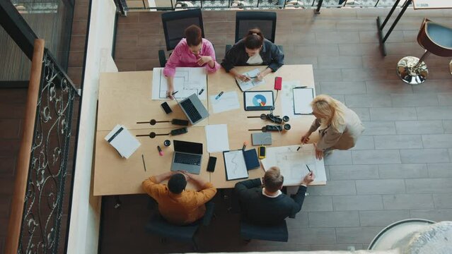 Group of colleagues working together on project during meeting in modern coworking. Top view
